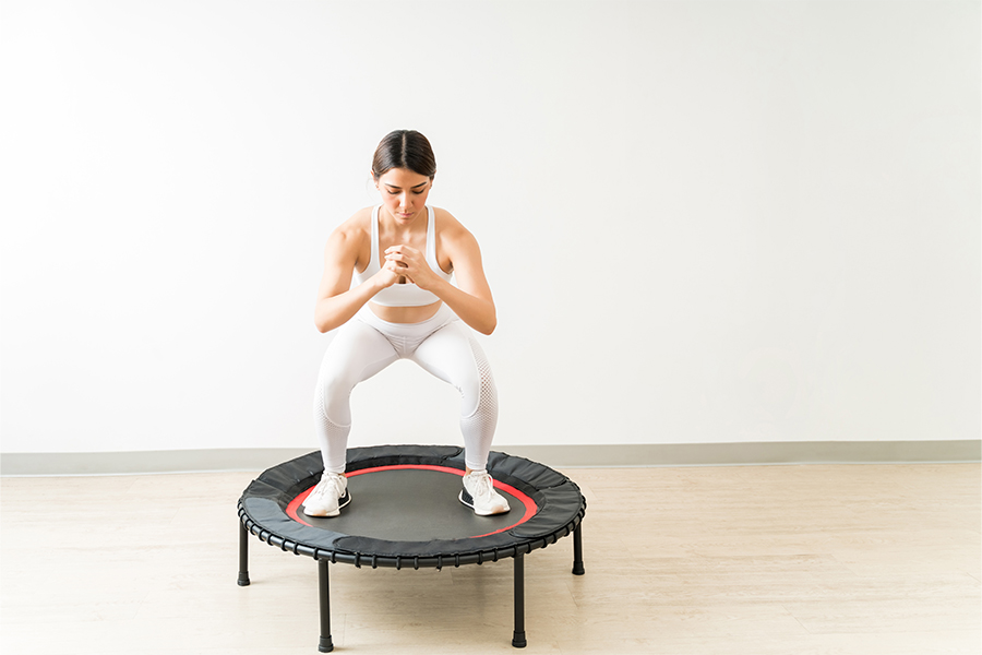 Ragazza esegue esercizi con il trampolino o tappeto elastico rebounding per dimagrire e tonificare il corpo
